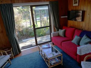 怀卡奈Theo's Cottage的客厅设有红色的沙发和大窗户