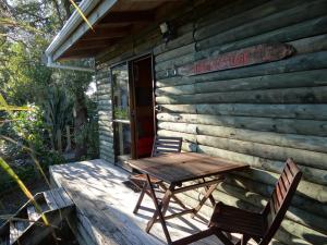 怀卡奈Theo's Cottage的小木屋门廊上的木桌和椅子