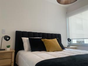 布宜诺斯艾利斯Departamento en Recoleta的卧室配有黑色和白色的床以及黄色枕头