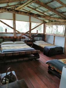佩雷拉Cabaña el Ensueño (GUADUA, BAMBU)的客房内设有两张床,铺有木地板,设有窗户。