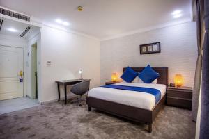 安曼Al Basem Hotel的酒店客房配有一张床、一张书桌和一张书桌。
