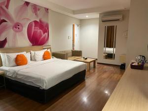 雅加达Grand G7 Hotel Pasar baru的卧室配有一张床,墙上挂有绘画作品