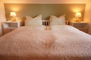霍尔斯泰因地区诺伊斯塔特FeWo Suite Spaltsberg am Binnenwasser的一间卧室配有两张带枕头和两盏灯的床。