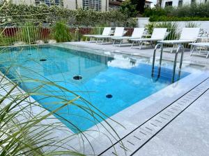 卢卡Villa Fedora Luxury Suites的一个带蓝色水和白色椅子的游泳池