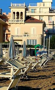 里米尼Villa La Torretta Luxury B&B - Adults Only -的海滩上一排草坪椅和遮阳伞