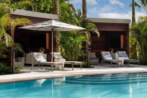 那不勒斯The Ritz-Carlton Naples, Tiburon的房屋旁的游泳池配有椅子和遮阳伞