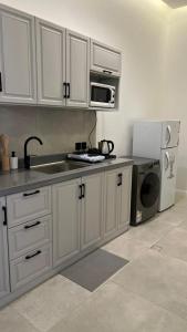 塔伊夫dana hotel apartments的厨房配有白色橱柜、水槽和冰箱。