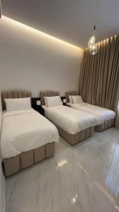 塔伊夫dana hotel apartments的配有白色床单的酒店客房内的两张床