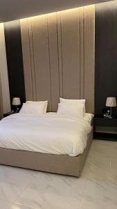 塔伊夫dana hotel apartments的卧室配有一张带白色床单和枕头的大床。