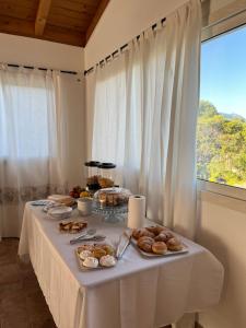 西尼斯科拉Sa Jacca Albergo Rurale的一张带食物的白色桌子,窗户