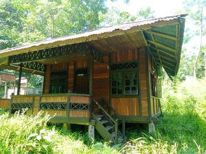 美娜多Lorenso Cottage的一座小木房子,在草地上设有门廊
