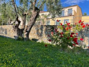 因佩里亚Villaggio RTA Borgoverde的建筑前方有红色花的石墙