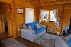 斯沃弗姆Bishy Barnabees country lodge with hot tub的小屋内带蓝色椅子的客厅