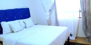 KakamegaMaridadi place的一张白色的床,上面有蓝色的床头板