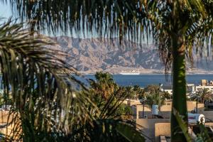 埃拉特Eilat Beach House的从棕榈树上欣赏到海洋和山脉的景色