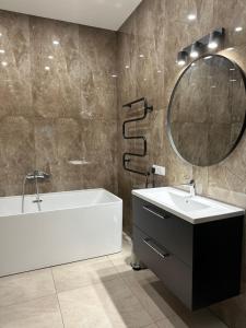 GinduliaiVilla BEBRŲ NAMAI with Hot Tub的带浴缸、水槽和镜子的浴室