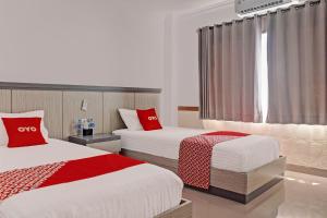 BanjarbaruOYO 92518 De Luna Hotel的酒店客房 - 带两张带红色枕头的床
