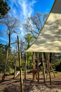 宁斯佩特Luxe boshuis Veluwe - Foss Lodge - luxury forest retreat的一个带白色天篷和木柱的游乐场
