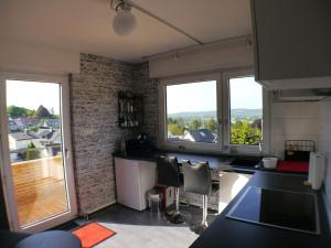 波恩Siebengebirgsblick的一间带2扇大窗户和阳台的厨房