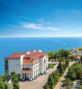 敖德萨卡多尔度假酒店的一座白色的建筑,有红色的屋顶,靠近大海