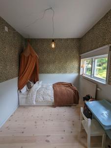 哥德堡30-tals villa med närhet till centrala GBG的一间卧室设有一张床、一个窗口和一张桌子