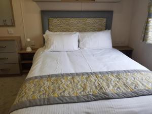 米尔福德昂西2 Bedroom Lodge, Milford on Sea的卧室配有一张带白色床单和枕头的大床。