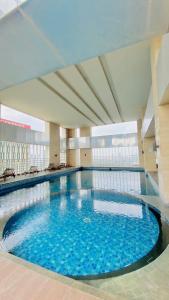 雅加达The H Tower Rasuna Suites Kuningan jakarta by Villaloka的大楼内一个蓝色的大型游泳池