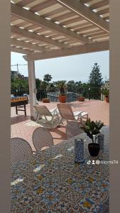 卡斯特拉玛雷帝斯达比亚La Terrazza Quisisana Sorrento Coast的凉亭下带桌椅的天井