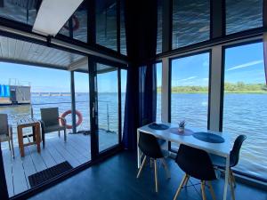 波莫瑞地区卡缅Hausboot- Domy na wodzie - Houseboat Porta Mare的配有桌椅并享有水景的客房
