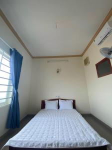 邦美蜀Khách sạn Ban Mê Xanh (Ban Me Xanh Hotel)的一间卧室配有一张带蓝色窗帘的大床