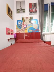 利沃诺Casa vacanze completa di tutto e anche di più的卧室配有红色的床,墙上挂有绘画作品