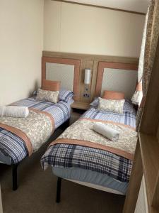 威尔汉姆2-6 guests Holiday Home in Durdle Door的小客房内的两张床,配有两张sidx sidx单人床