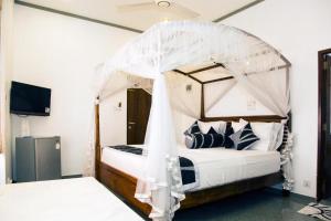 尼甘布苏丽亚拉纳住宿加早餐旅馆的一间卧室配有一张带天蓬的床