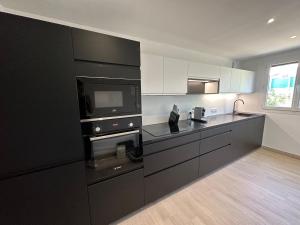 卡尔热斯Alivu - Appartement Moderne Avec Terrasse的厨房配有黑色橱柜和微波炉