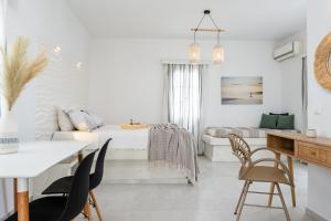 米科利维亚Diamantis Studios&Apartments的白色的客房配有一张床、一张桌子和椅子