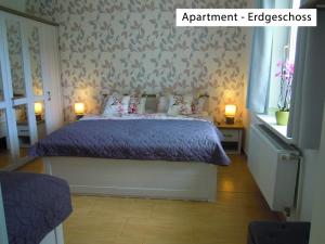 韦尼格罗德Ferienwohnung Wolfsholz的一间卧室配有一张带紫色棉被的床和两盏灯。