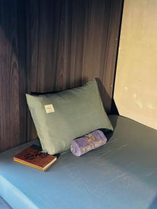 胡志明市T Zone Hostel的一张带枕头的床、一本书和一张钱包