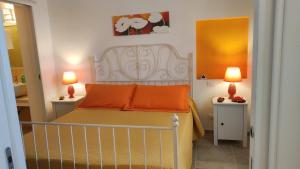 莫诺波利Villini di Sant'Andreas的一间卧室配有一张带橙色枕头的床和两盏灯。