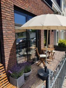 海边的艾格蒙特Zilt aan Zee的庭院配有遮阳伞和桌椅。