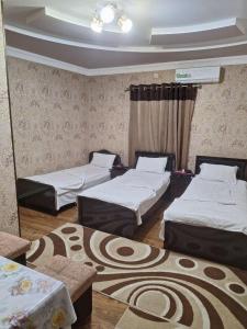 撒马尔罕B&B Giza Registan的带三张床的客房,铺有地毯