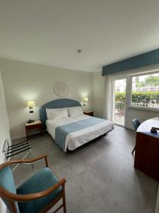 马尔切西内怡东湾酒店的卧室配有床、椅子和窗户。