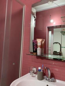 乌尔齐尼Guest House Nuhii的浴室设有水槽、镜子和粉红色瓷砖