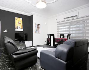 洛美Villa Flo Residence的客厅配有黑色椅子和电视