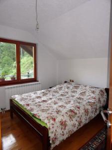 RožajeWeekend house Grahovača的一间卧室配有一张带花卉棉被的床和窗户。