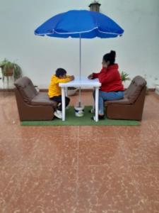 巴兰卡HOTEL CASTILLO MAGICO (EX CHAVIN SEÑORIAL?的两个人坐在桌子旁,拿着雨伞