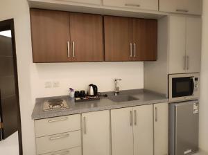 艾卜哈Kyan Park Abha Hotel的厨房配有白色橱柜、水槽和微波炉