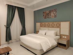 艾卜哈Kyan Park Abha Hotel的卧室配有带绿色窗帘的大型白色床