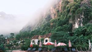 峰牙Central Backpackers Hostel - Phong Nha的山前带桌子和遮阳伞的建筑