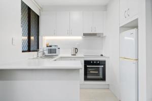 堪培拉麦卢卡公园服务公寓的白色的厨房配有白色橱柜和冰箱。