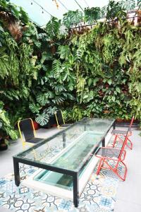 胡志明市AMANGO HOSTEL的绿色墙前的玻璃桌子和椅子